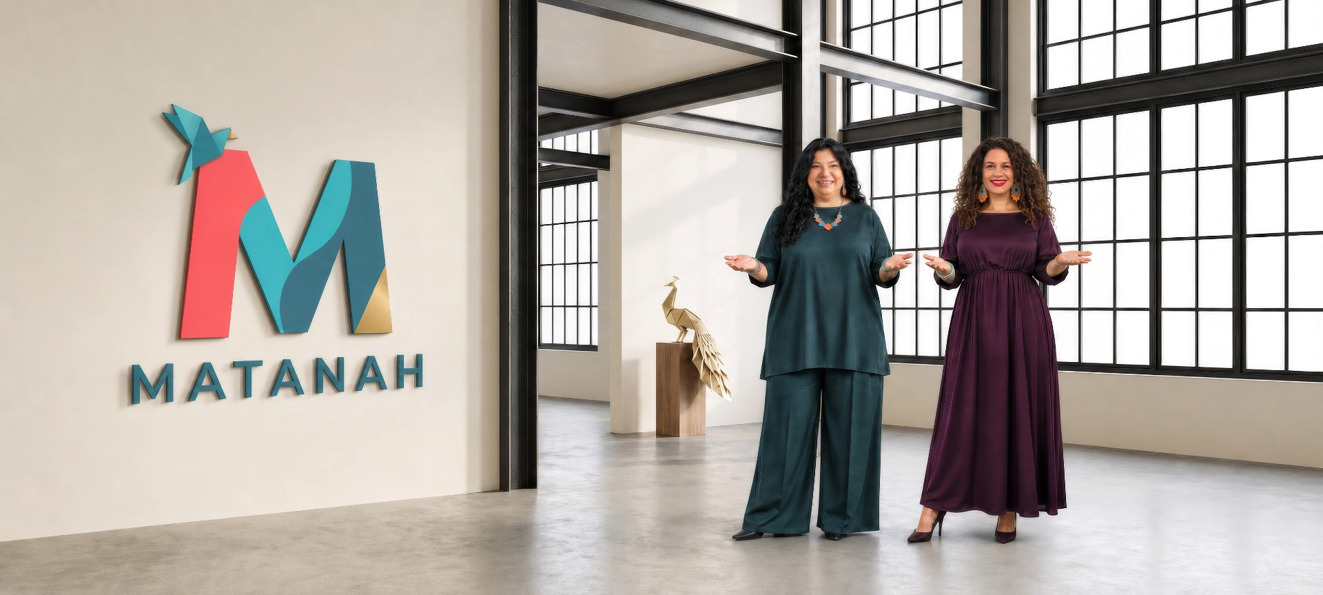Matanah founders Shelly Guy and Sofia Seitchik welcoming visitors inside the Matanah hall beside the logo and gold origami peacock